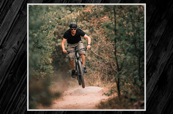 Photo of male cyclist riding a bike on an ordinary track in nature.