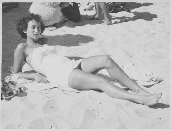 Original, B&W photo of a lady sunbathing on beach.