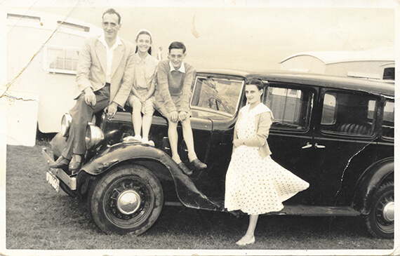 Original B&W photo, family sitting on the hood of a vintage car.