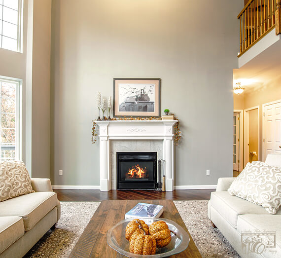 Image of the sitting room with a fireplace – now with a cozy fire added to the fireplace.