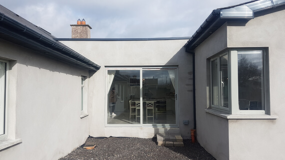 Image of a newly renovated house with gray walls and a neglected looking courtyard resembling a building site.